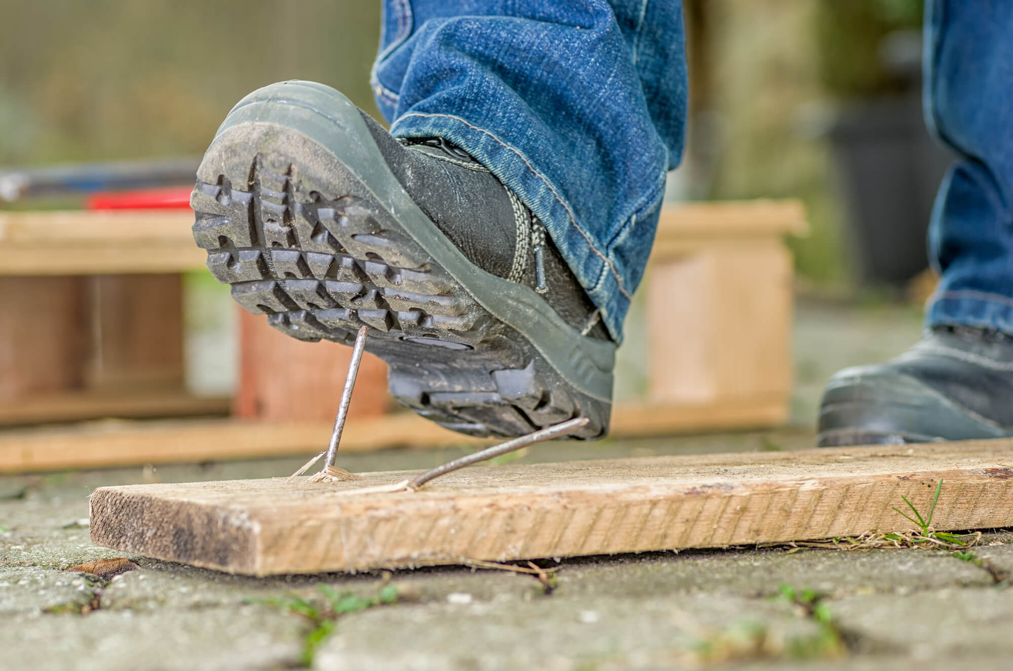 builder wearing a safety boot about to step on a nail