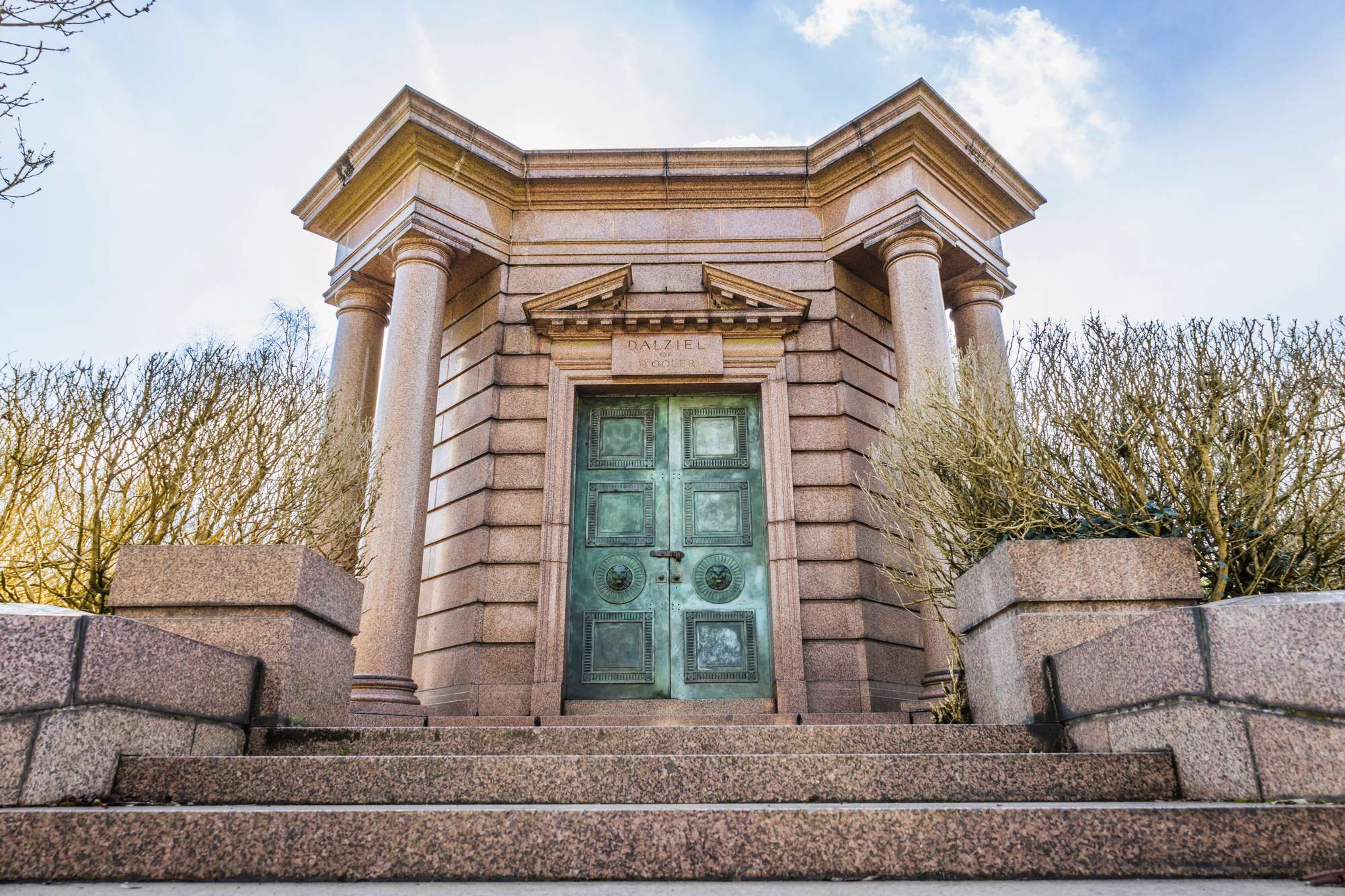 Highgate cemetery entrance with grand stone pillars and-green doors