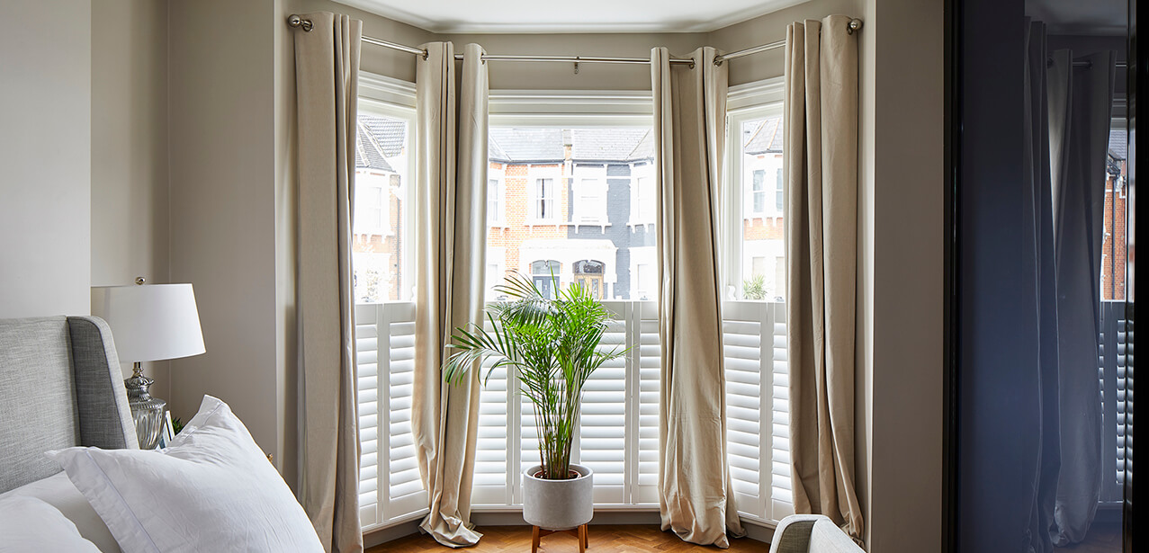 Victorian windows with beige curtains in bedroom