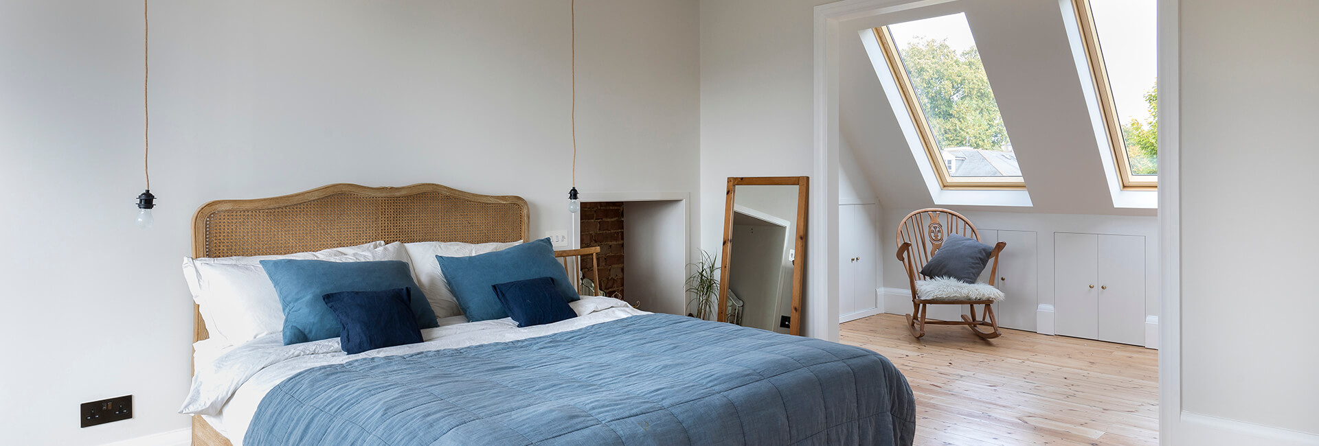 Modern attic bedroom with blue bedding and skylights