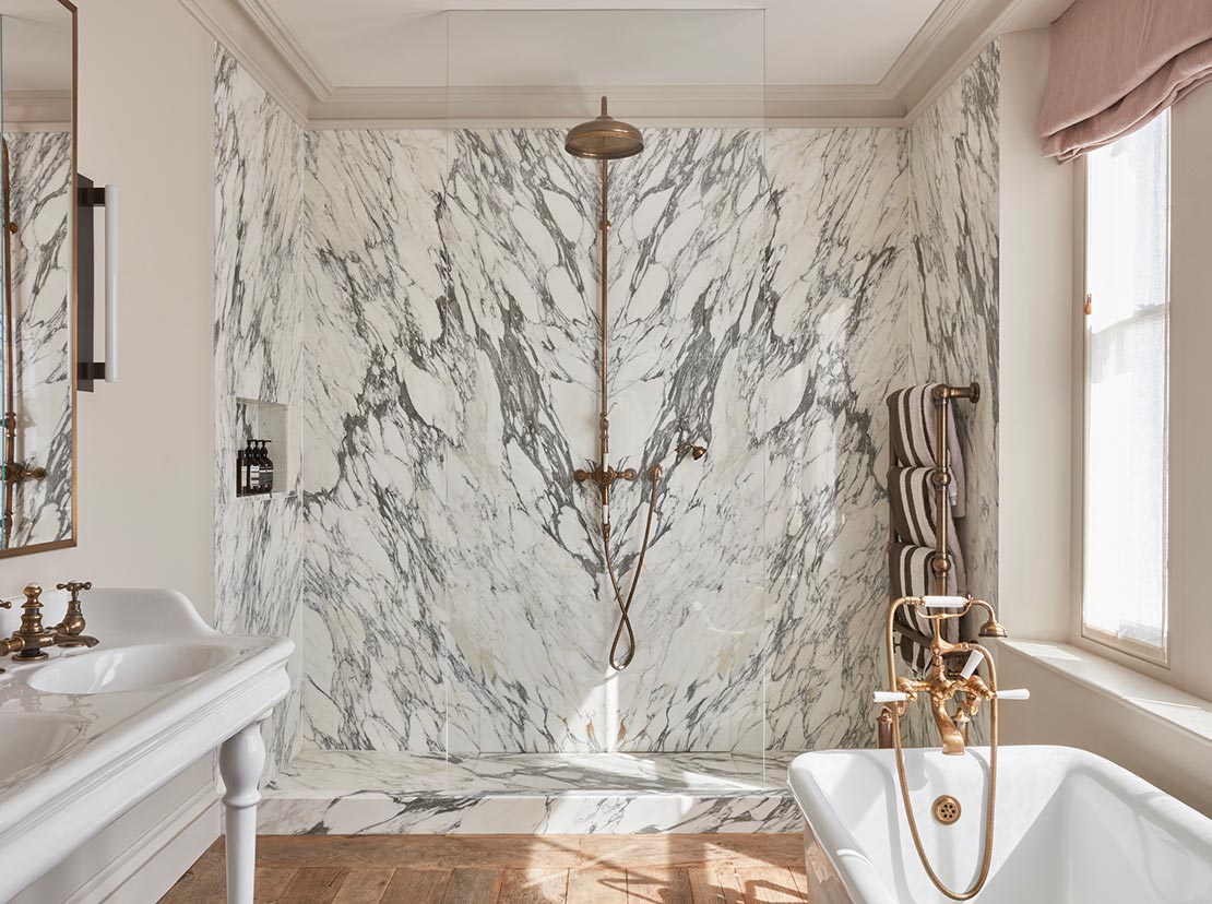modern bathroom with marbled walls, freestanding bath tub and dual sink