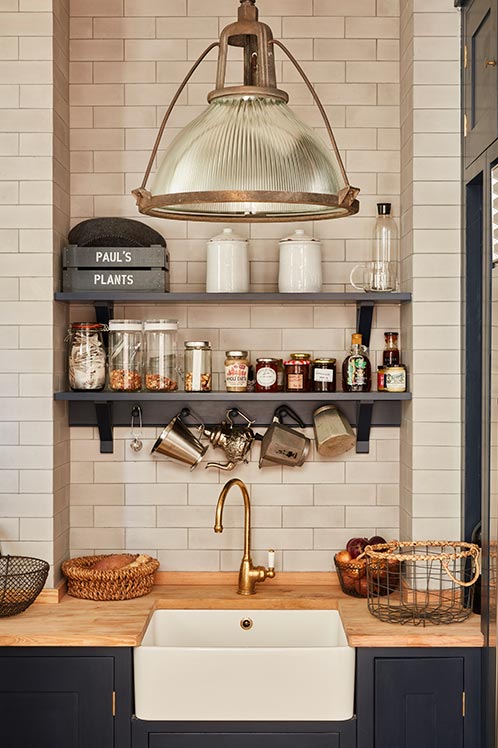 kitchen with farmhouse sink, wooden countertop and suspended spice rack