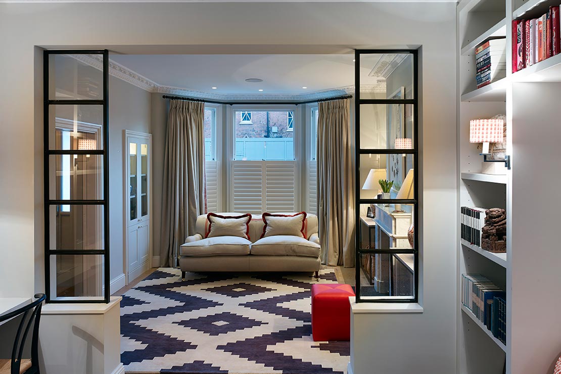 open plan lounge area with cream couch, wooden floors, mantel and book case