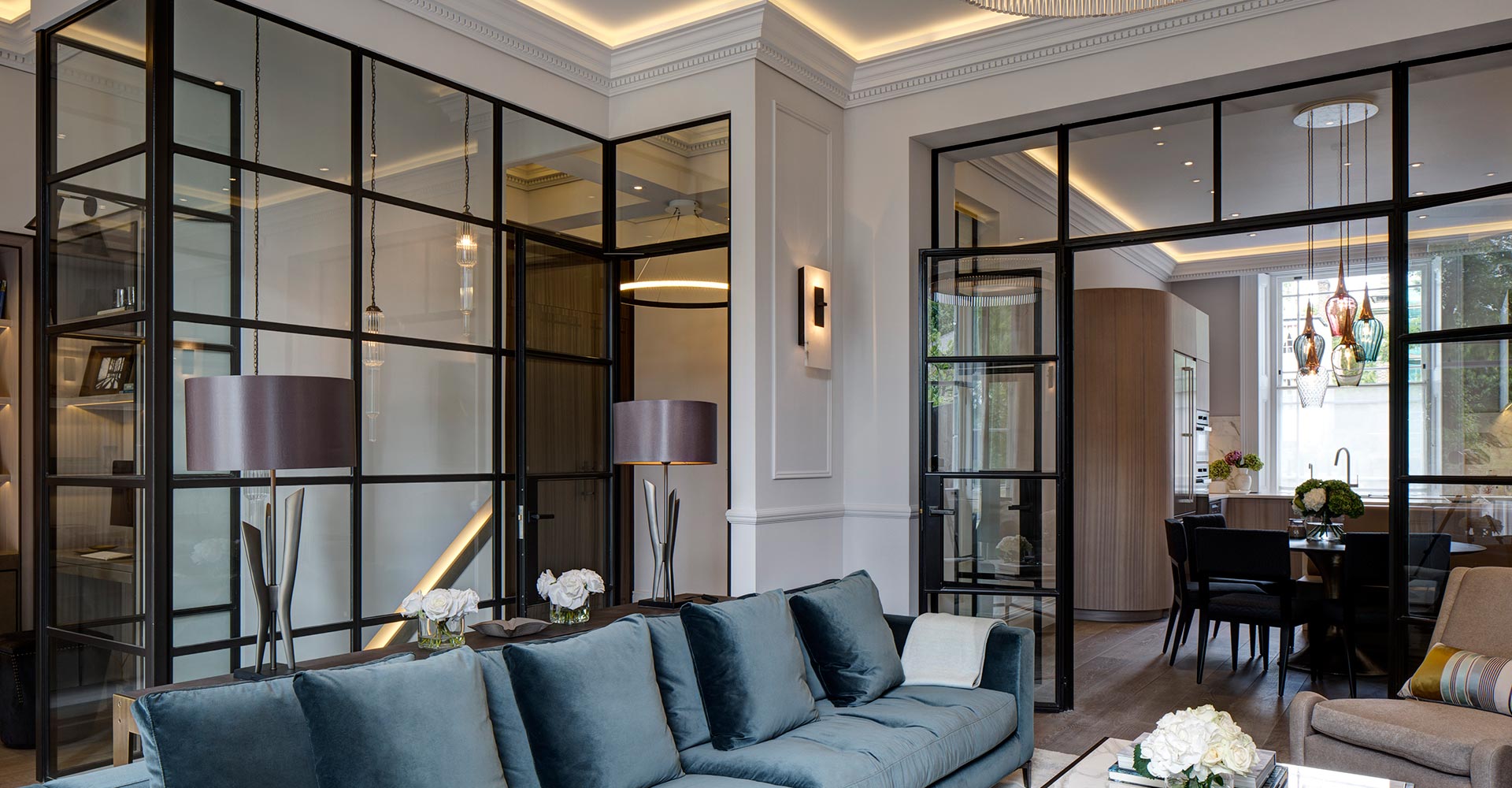 lounge with velvet sofa, black paned glass windows and doors leading to dining area