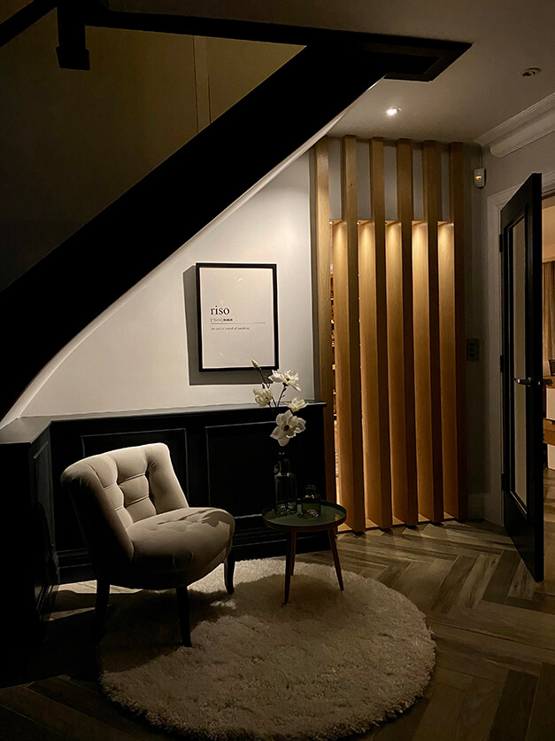 sitting area beneath staircase with comfy chair and fluffy rug