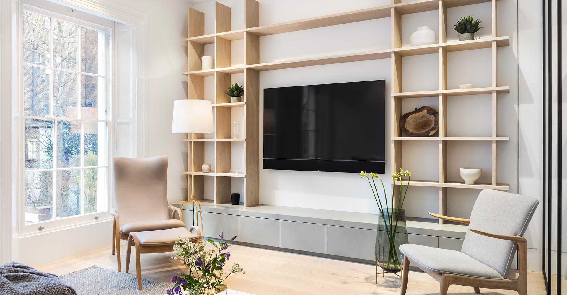 modern TV room with large wooden display case and grey suspended cabinets in Clanricarde Gardens London