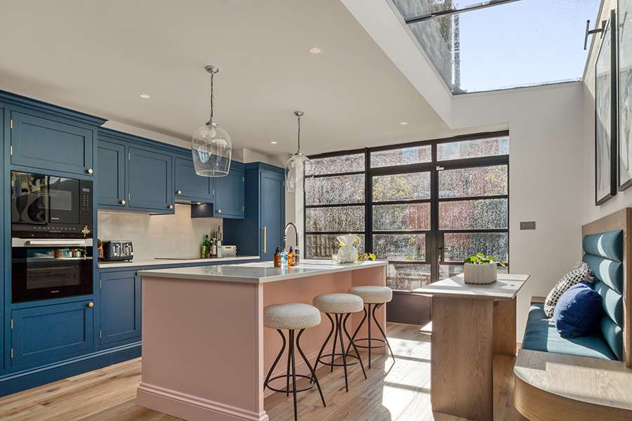 Navy blue cabinets with pink kitchen island and skylight
