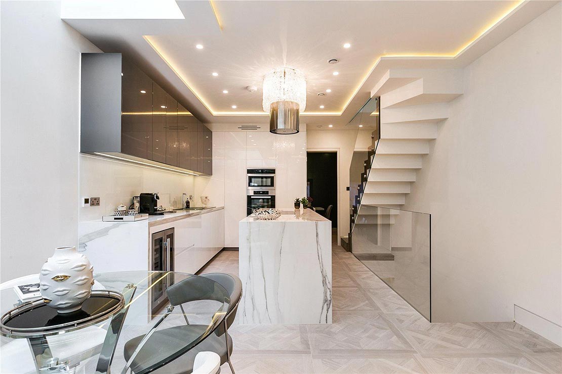 modern white kitchen with, grey cabinets, drum chandelier, marble kitchen island and dining area with glass top table