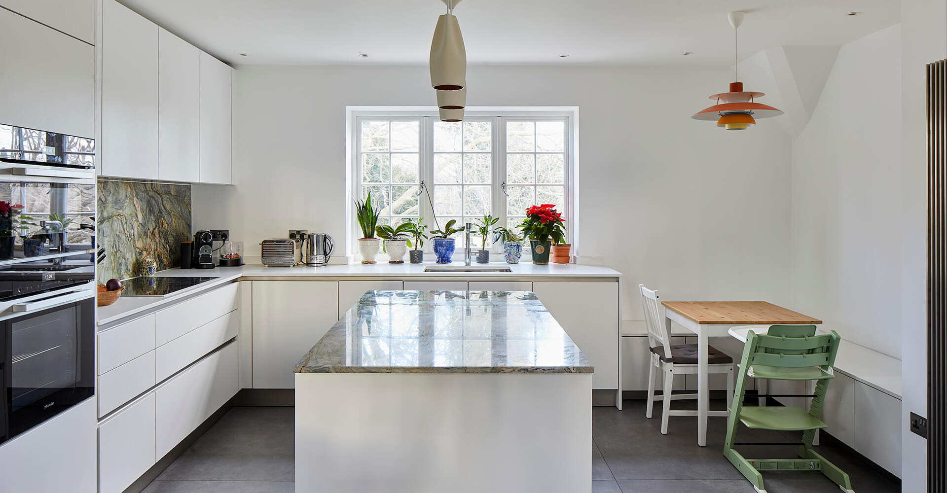 modern whtie kitchen with wall overs, garden view and marble-top island