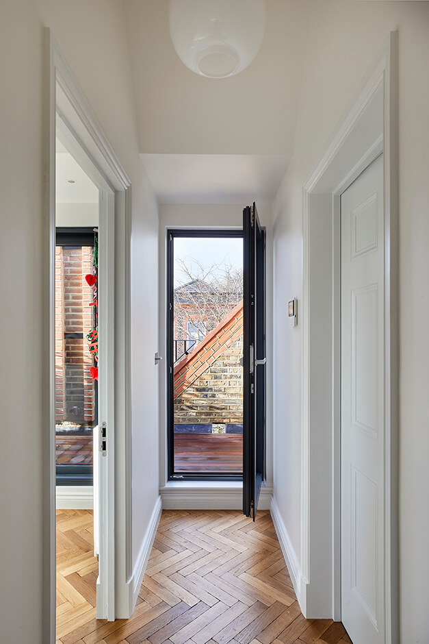 hallway with wooden flooring and black paned glass door leading to patio