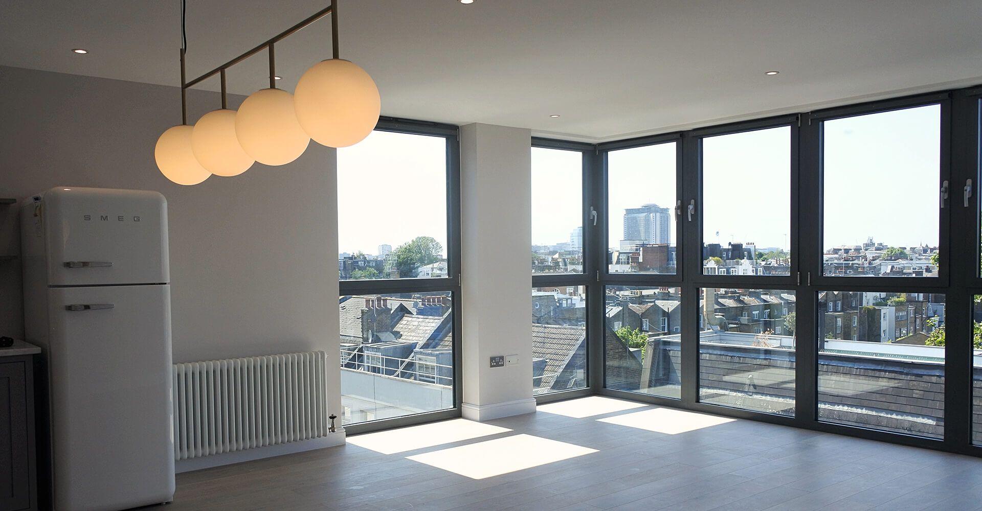 large room with radiator, wooden flooring and black paned windows with city view