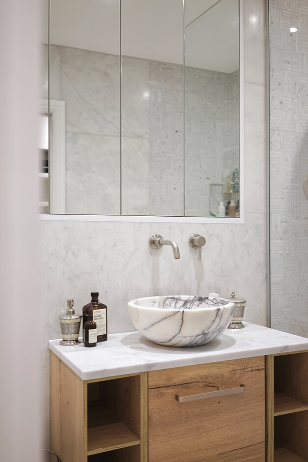 bathroom with marble bowl sink, wooden cabinet and built-in mirror cabnets