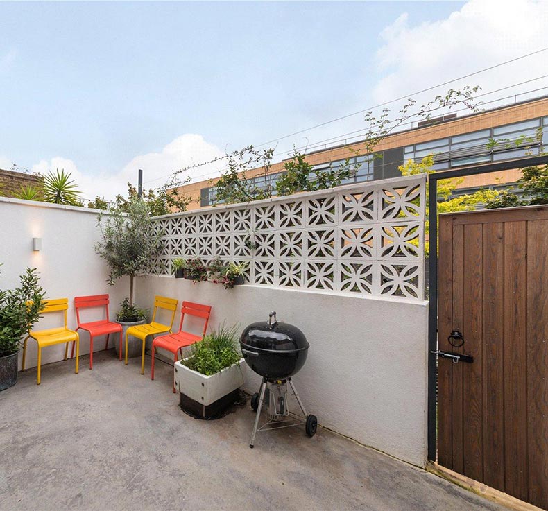 patio next to kitchen with chairs and grill