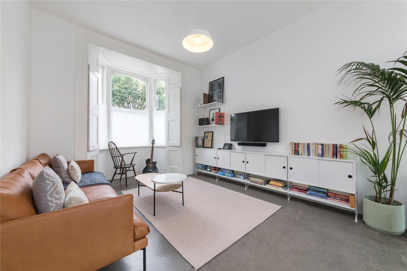 modern lounge area with large grey tiles, tan sofa and white display cabinets