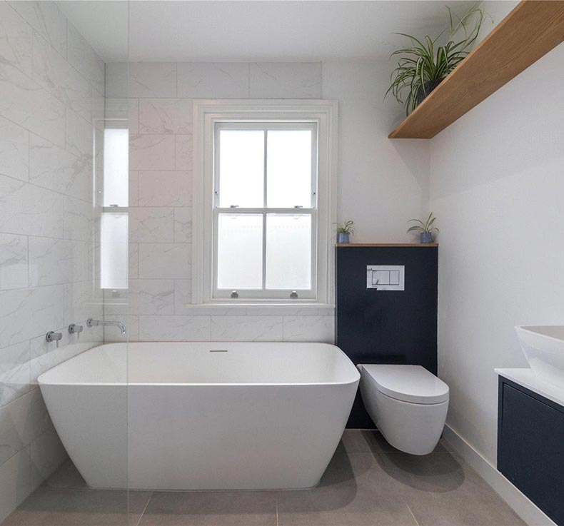 large white modern tub with toilet and large white brick wall tiles