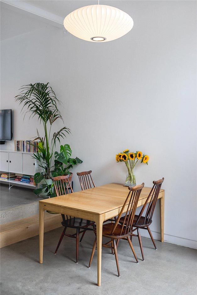 small dining area with modern lighting, wooden table adn simple chairs