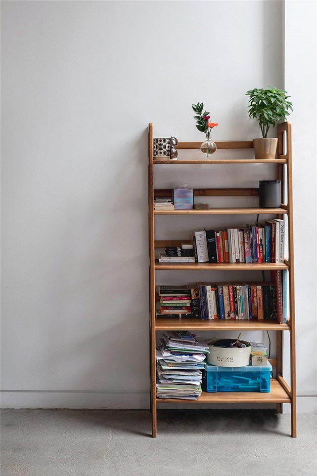 simple wooden bookcase against white wall with grey flooring