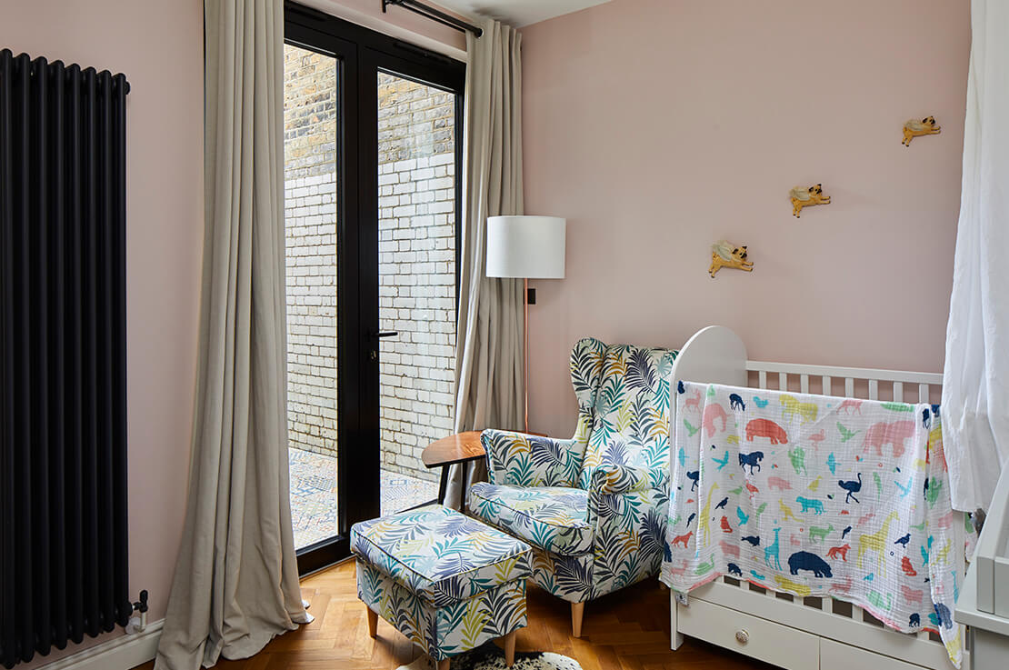pink toddler room with armchair and cot bed