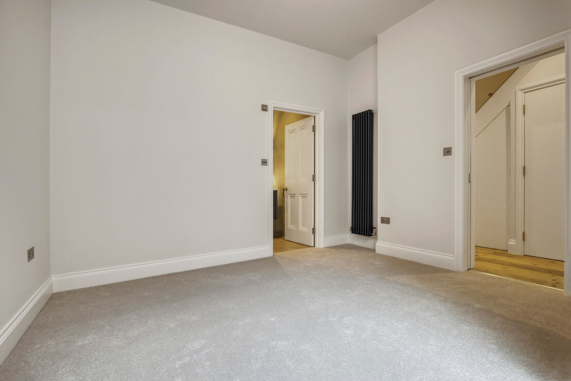 Modern empty bedroome interior design with light taupe walls and vertical radiator