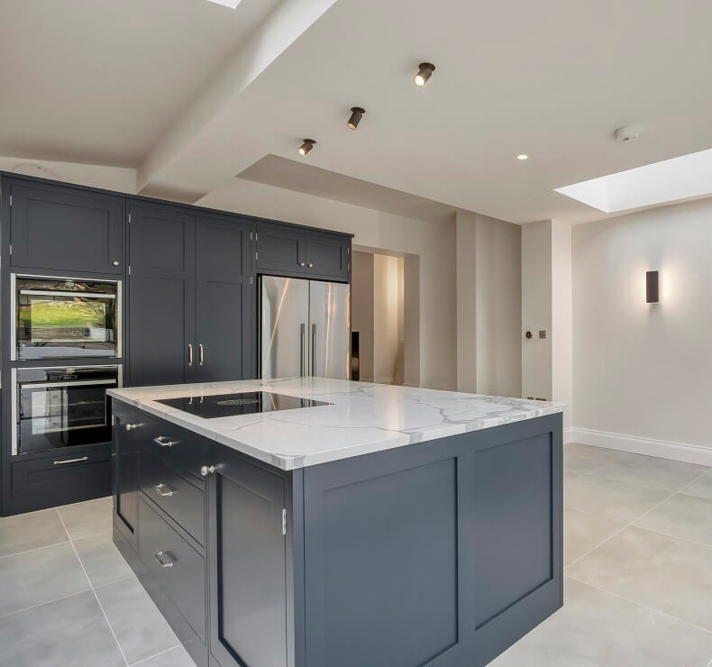 Modern kitchen Interior - Light grey kitchen cabinets and dark taupe flooring in a open plan kitchen with an island.