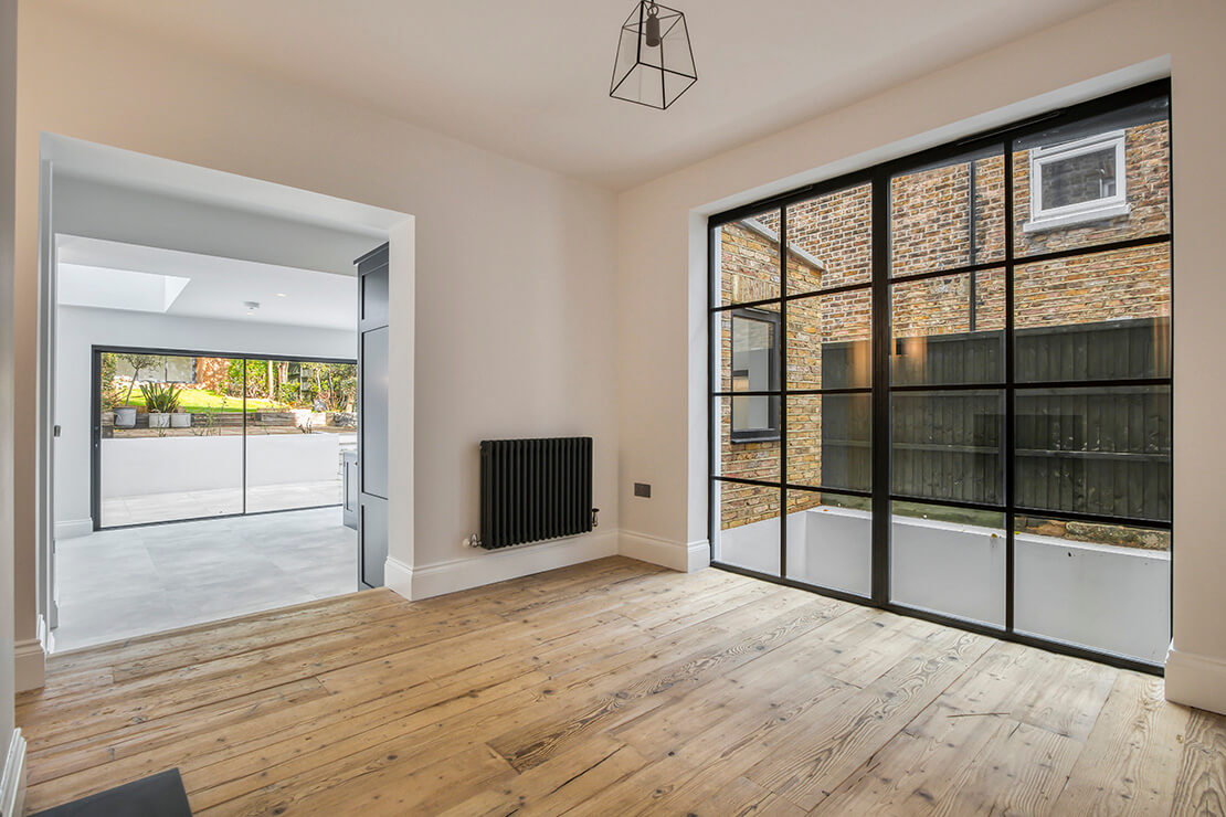A modern domestic room interior with bifold doors, and dark brown wood material flooring design.