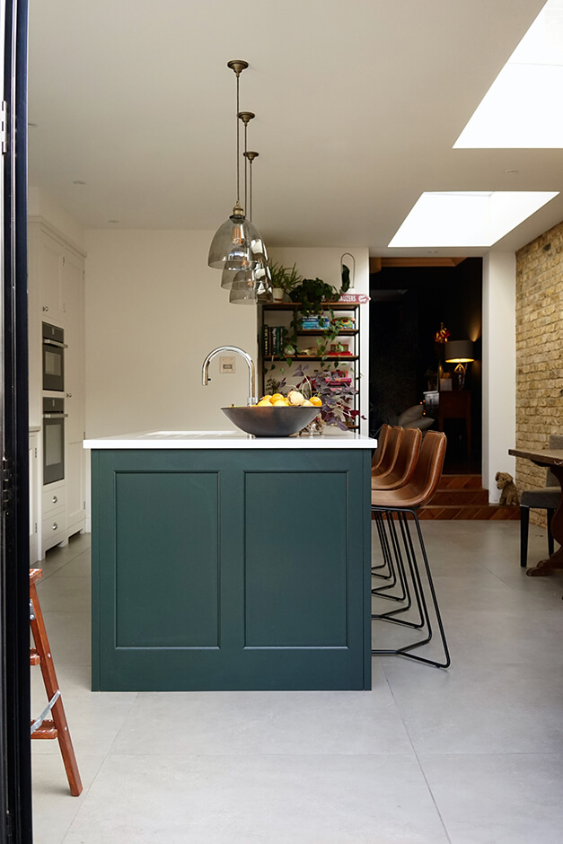 modern kitchen with large white floor tiles adn interior brick wall