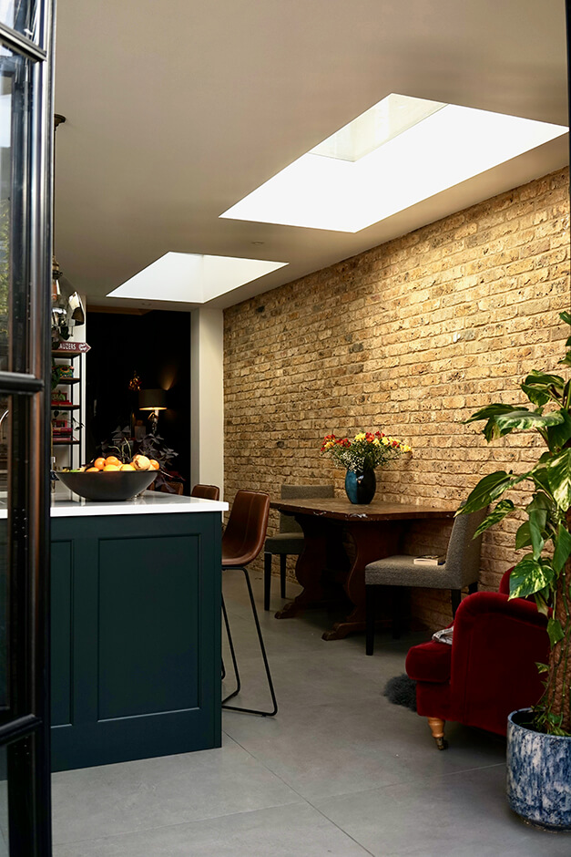kitchen with large tiled floors, skylight and brick wall interior