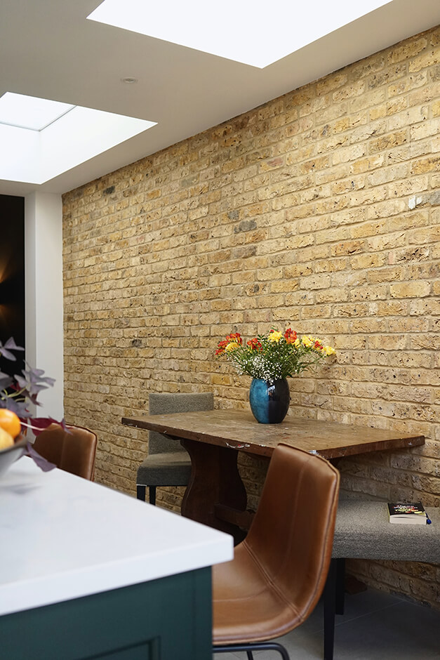 kitchen with brick interior wall, skylight and modern kitchen island with white top