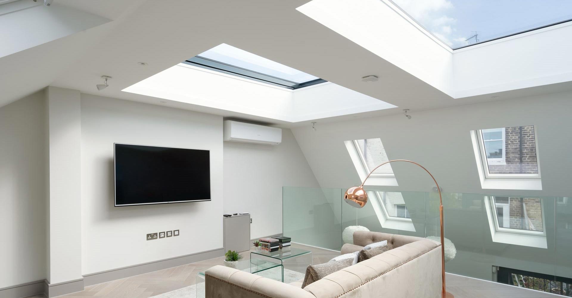 upstairs lounge area with suspended TV, wooden flooring, and skylight