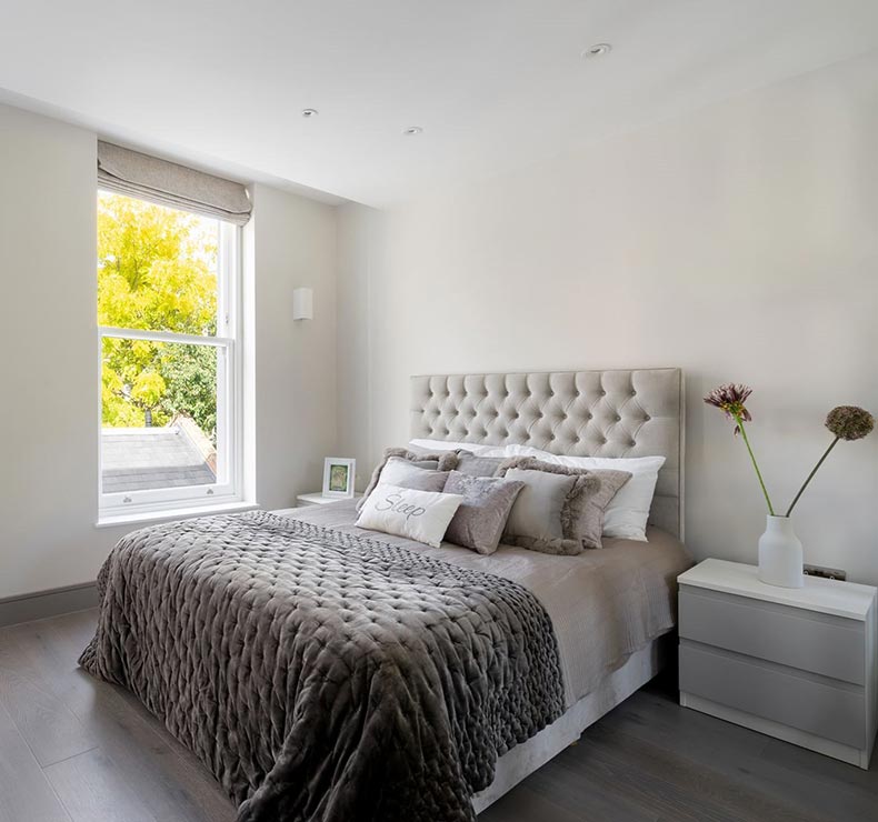 bedroom with twin bed, wooden flooring, large window and bed side table with drawers