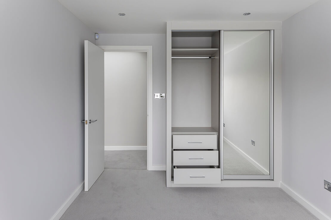 white and grey bedroom with closet door mirror and carpeted floor