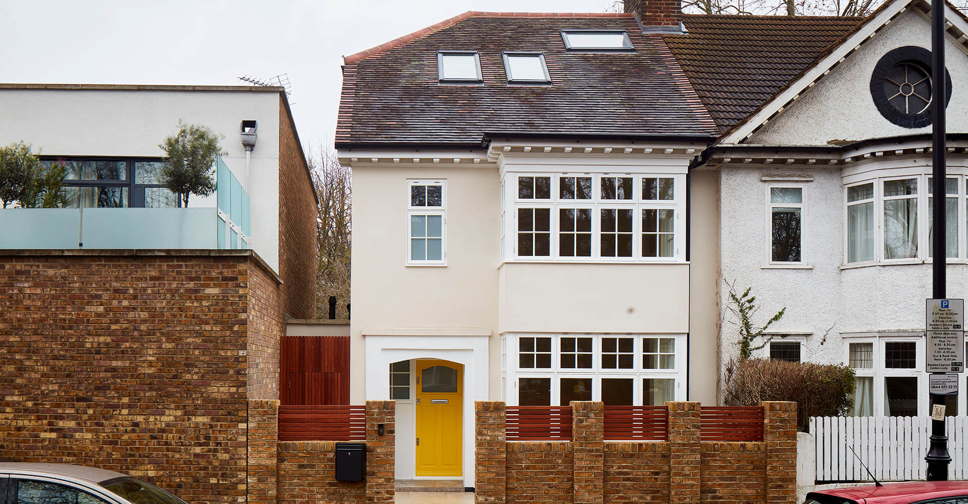 large white house exterior with brick fence and tiled roofing