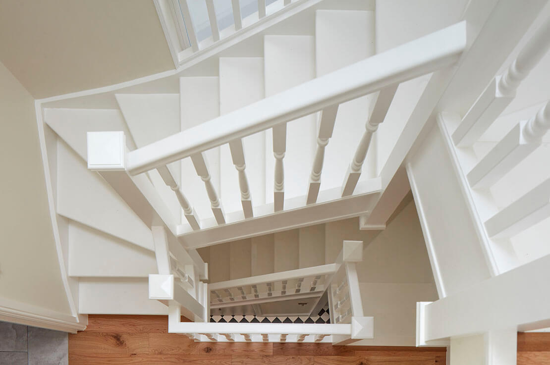aerial view of white staircase with white wooden railing