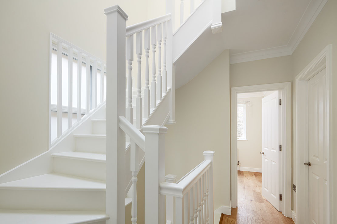 white staircase with white wooden railing, cream white walls ad wooden floors