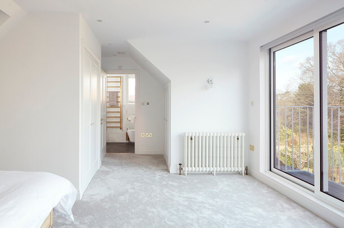 large white bedroom with carpeted floor, wardrobe, ensuite, radiator and large windows