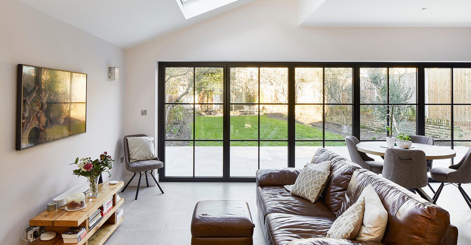 open plan lounge and dining room with patio and garden view through black paned windows