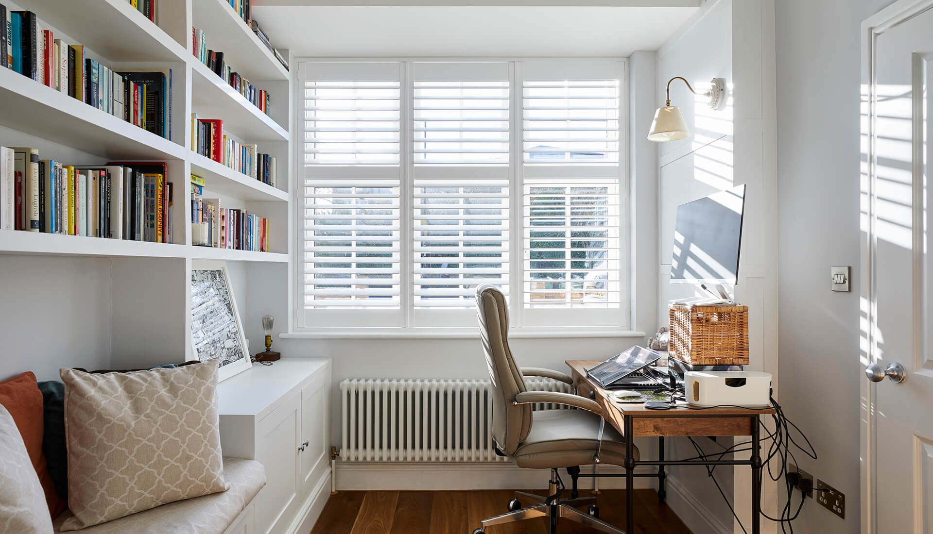 home office with built-in shelves, louvre blinds and wooden flooring