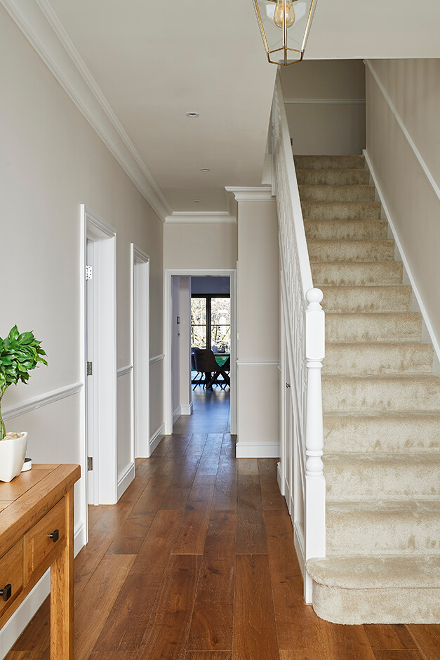 entrace with wooden flooring, carpeted staircase with white railing