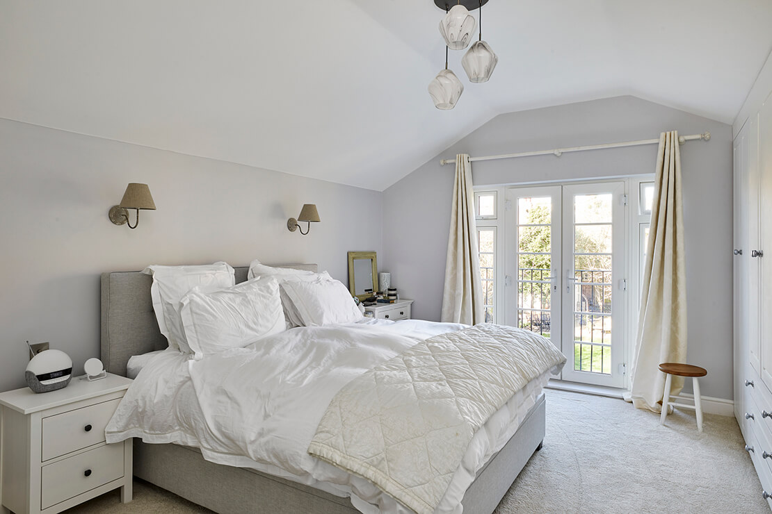 large bedroom with carpeted floor, balcony, modern chandelier and quuen size bed