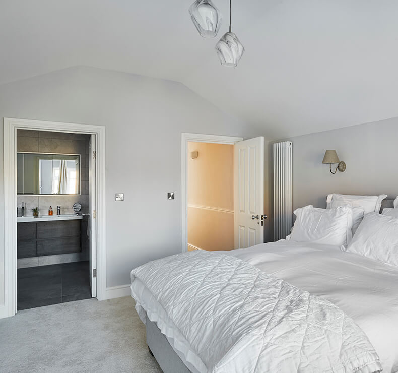 carpeted bedroom with modern grey ensuite bathroom