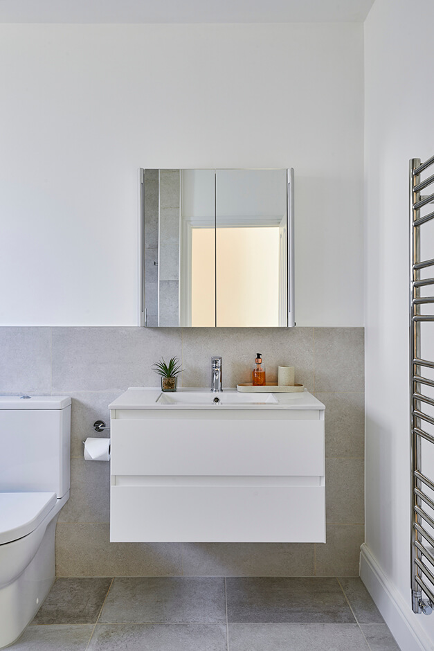 toilet with adjacent sink with cabinet and wall mirror