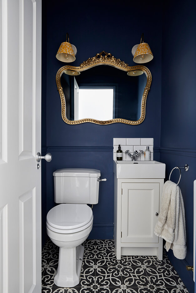 dark blue water closet with white toilet, white sink and mirror
