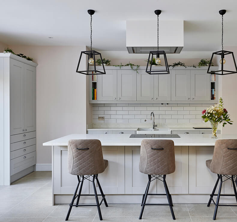 open plan white kitchen with white kitchen island, upholstered bar stools and induction cooktop 