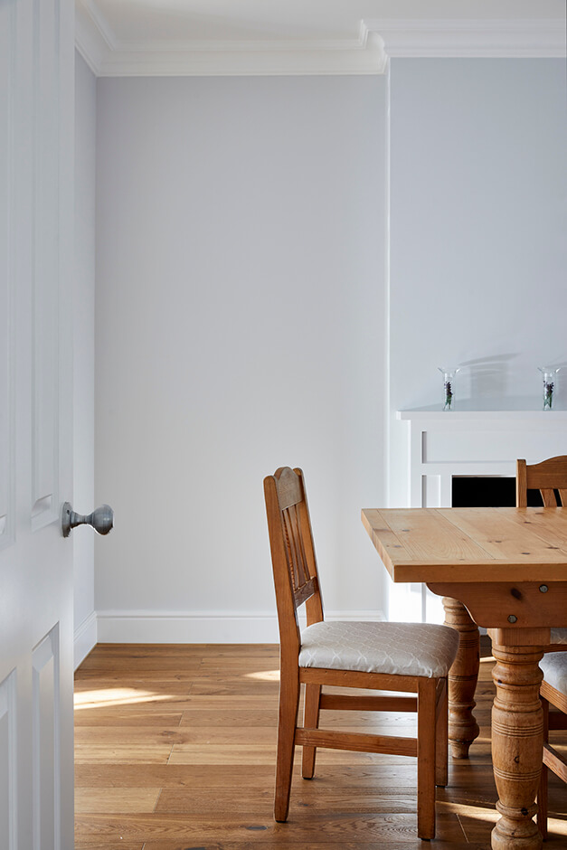 white dining room with wooden flooring and mantel