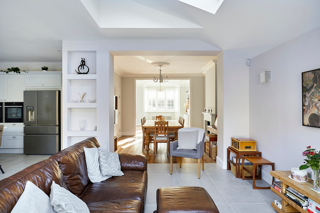 open plan dining room with chandelier and louvre blinds and lounge with skylight