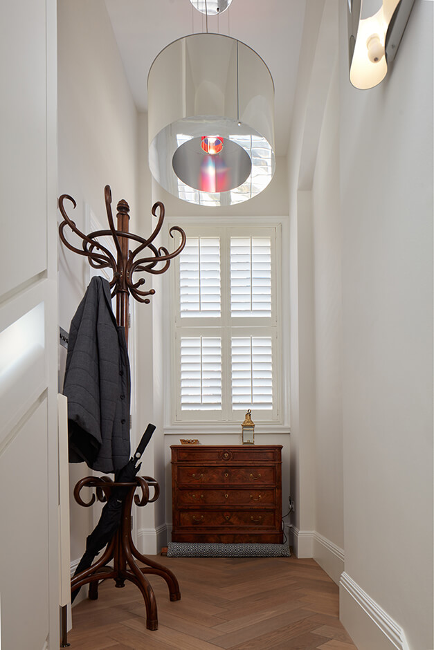 hallway with wooden dresser, louvre blinds and coat stand