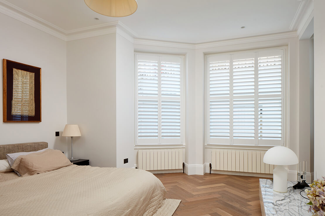 large bedroom with wooden flooring and louvre blinds