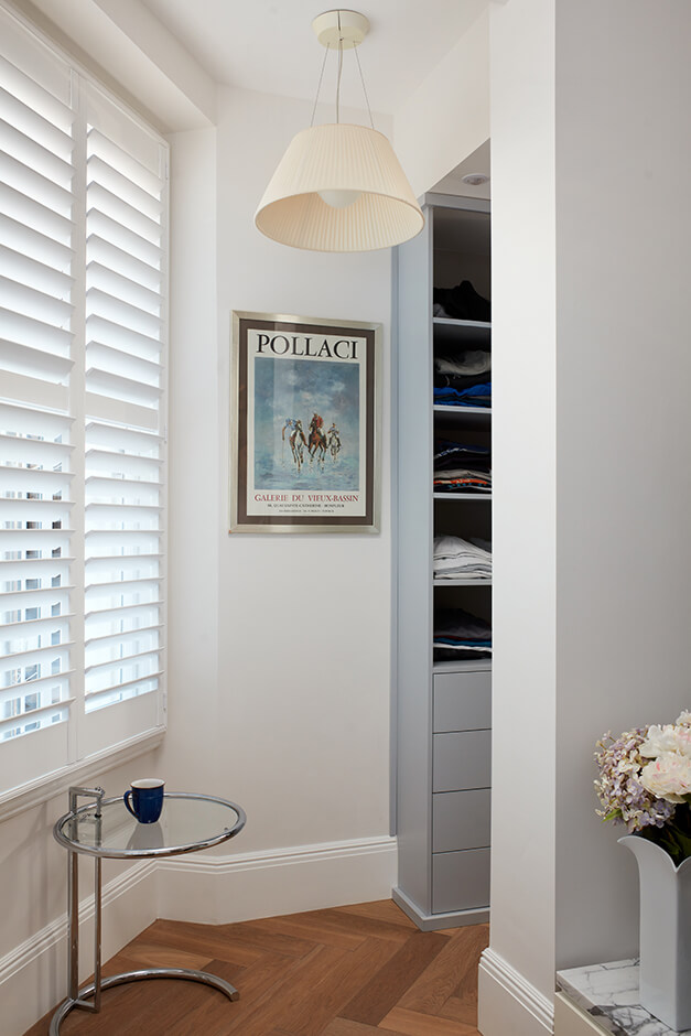 small walk in closet with grey cabinets, wooden flooring and louvre blinds