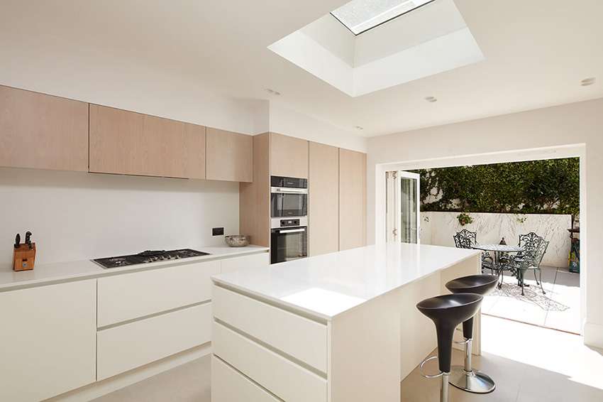 Beige and white kitchen extension with bifold doors and skylights