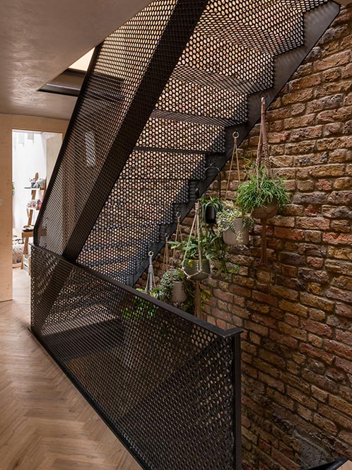 staircase with mesh railing and exposed brick wall